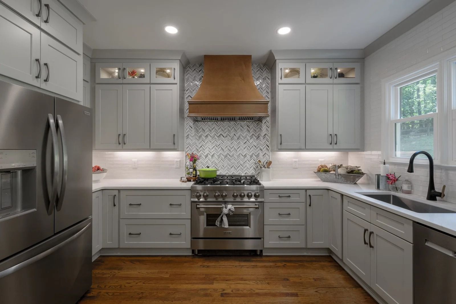 Modern kitchen with gray cabinets, stainless steel appliances, and wood floors.