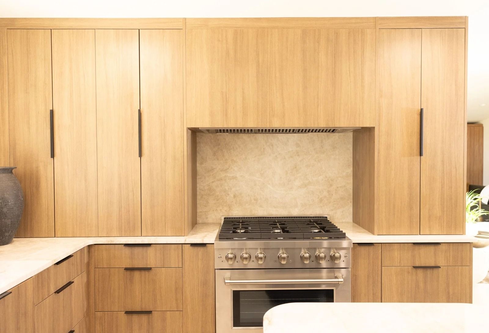Wooden kitchen cabinets surround a stainless steel oven and range with a light-colored countertop.