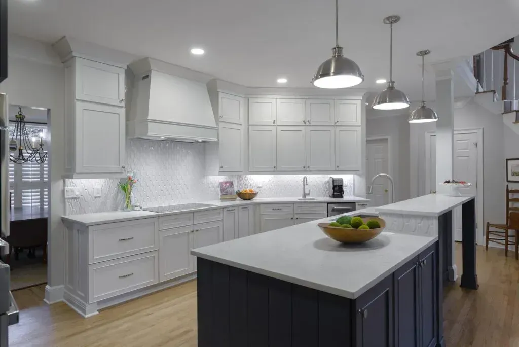 Modern white kitchen with two islands and stainless steel pendant lights.