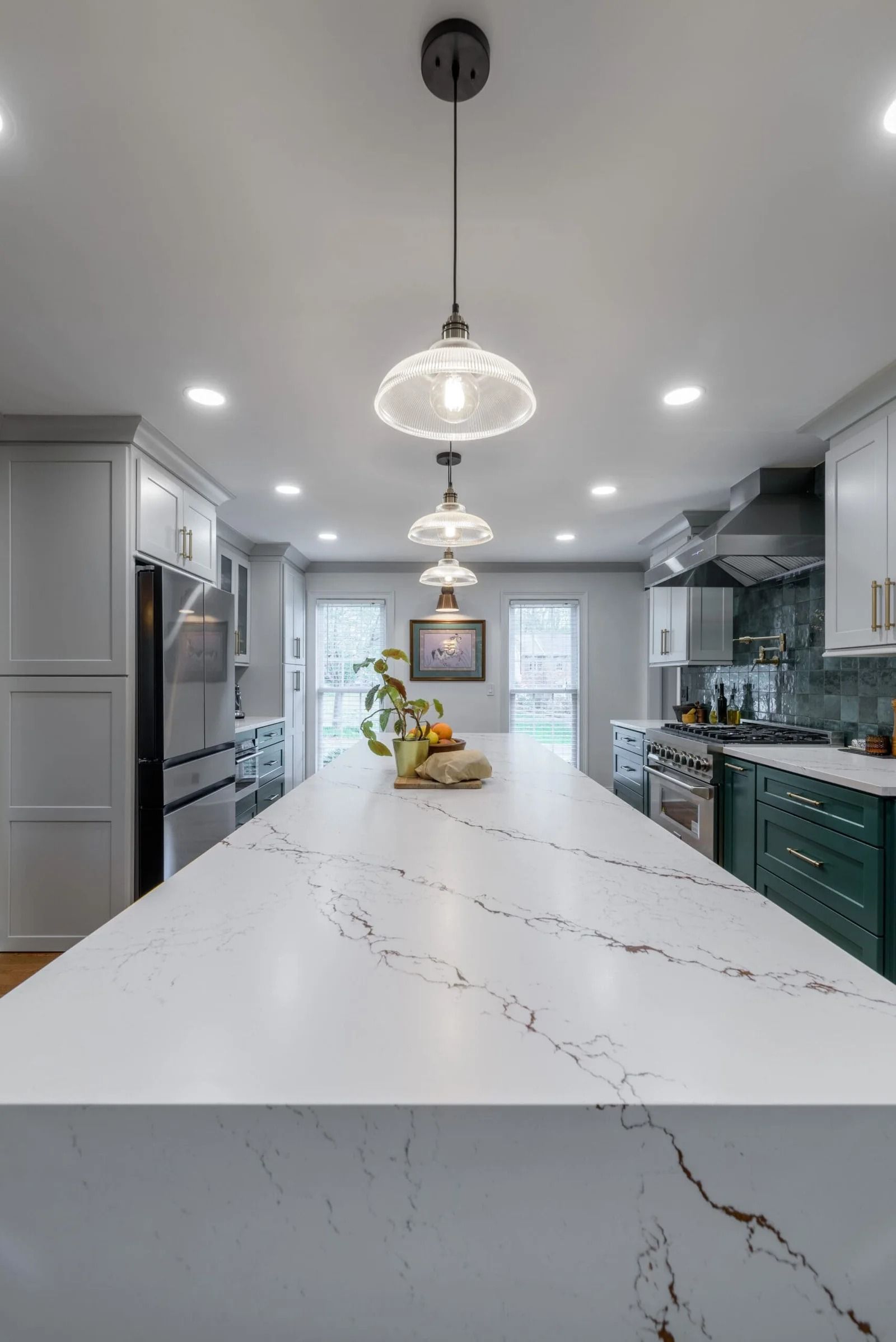 Modern kitchen with a long white countertop island and pendant lights.