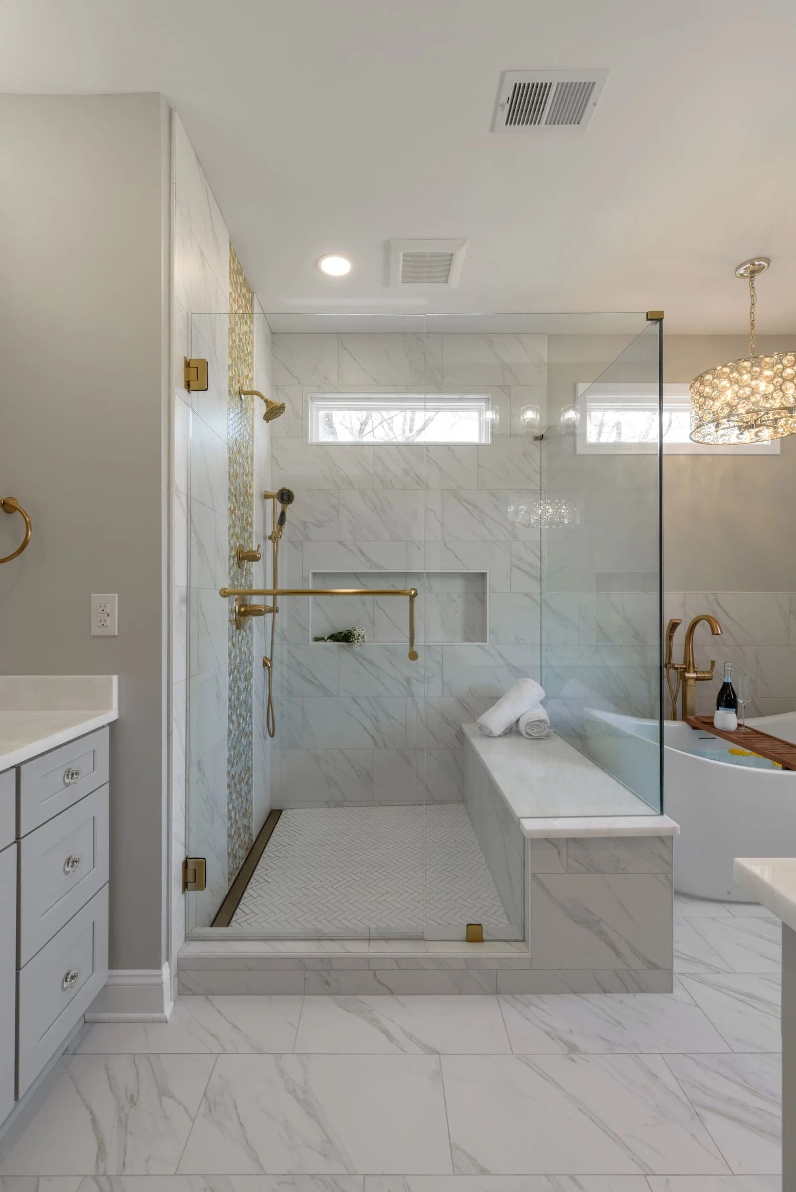 Modern bathroom with a marble shower and gold fixtures.