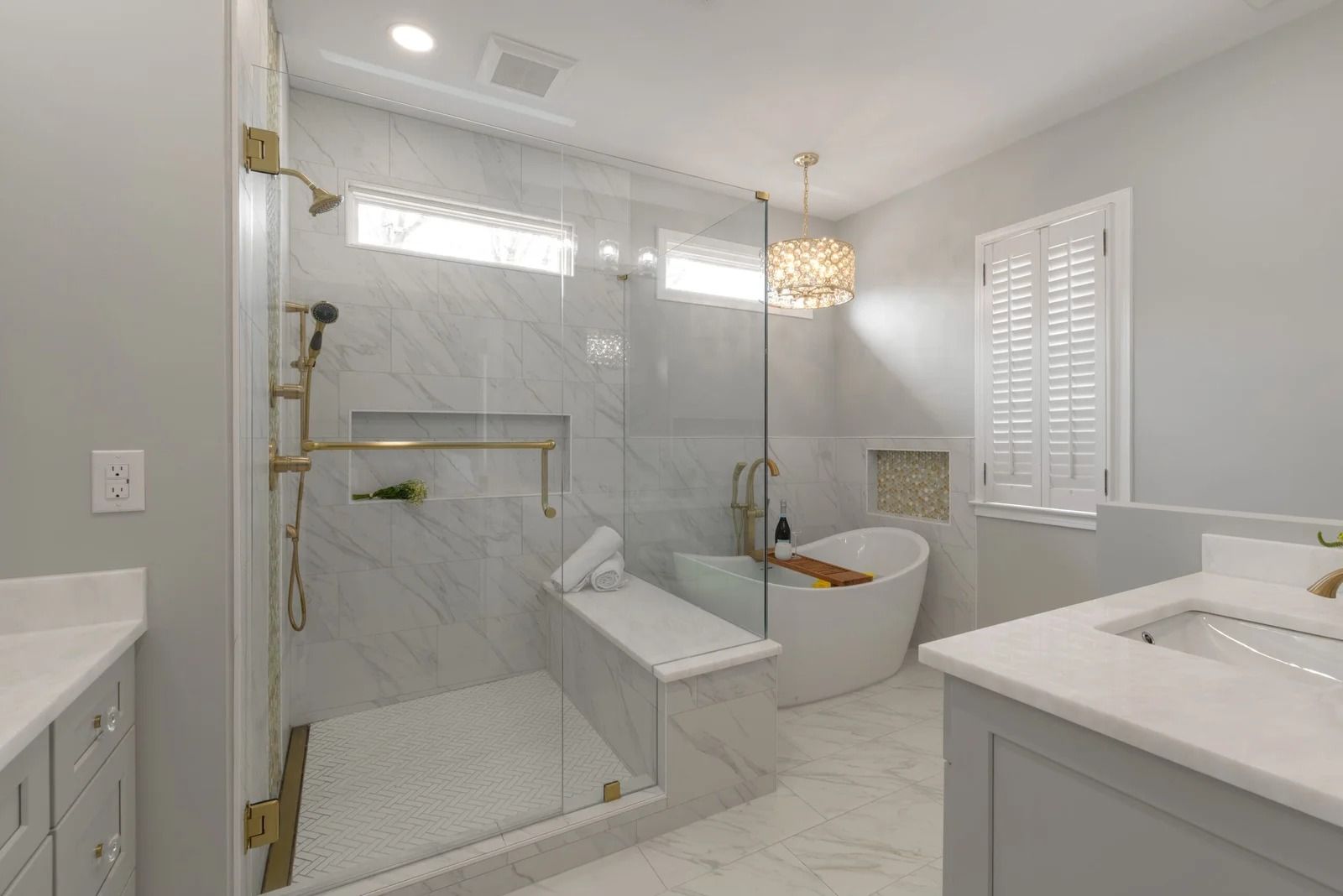 Luxurious bathroom with glass shower, soaking tub, light gray cabinets, and marble-like tile.