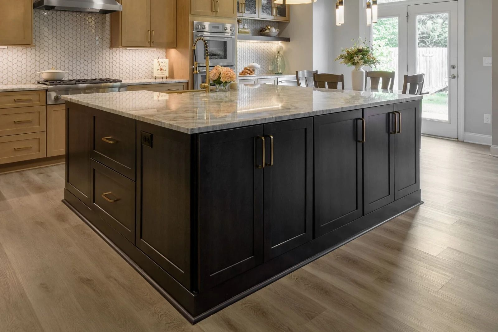 Black kitchen island with gold hardware and marble countertop.