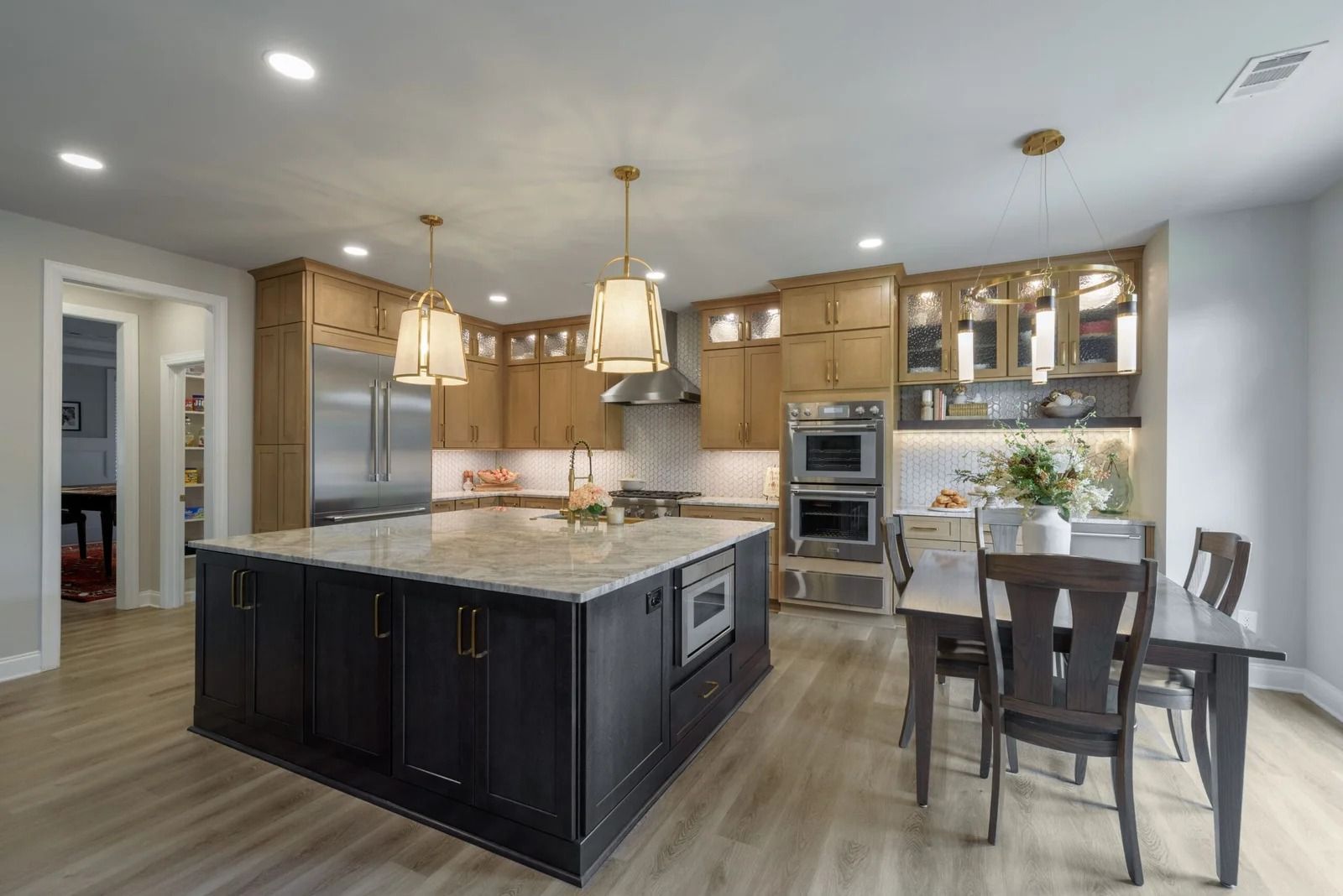 Kitchen with a large island, wooden cabinets, stainless steel appliances, and a dining table.