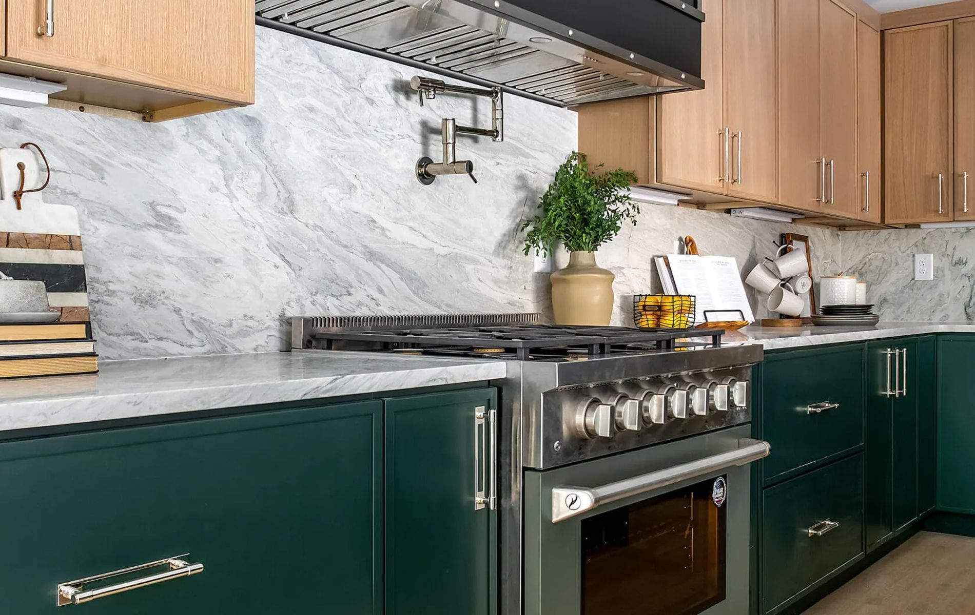 Green kitchen cabinets with a marble backsplash and stainless steel appliances.