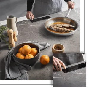 Person cooking fish in a pan on a countertop, with oranges, spices, and a pitcher.