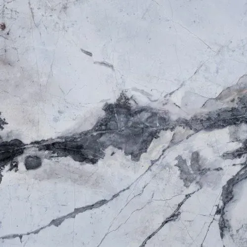 White marble slab with grey veining and abstract dark areas.