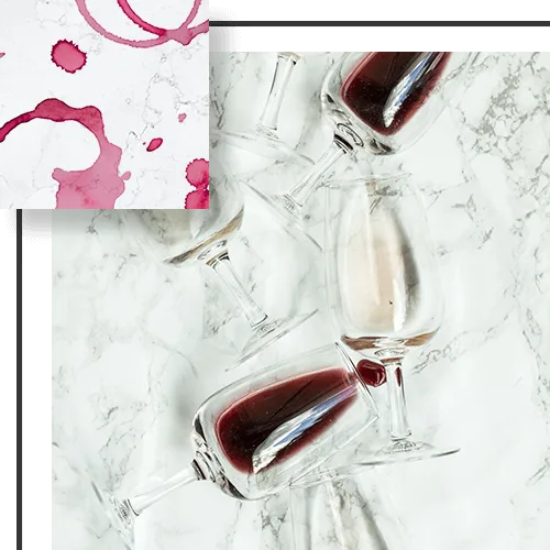 Wine glasses, some filled with red wine, on a marble surface, with wine stains in the corner.