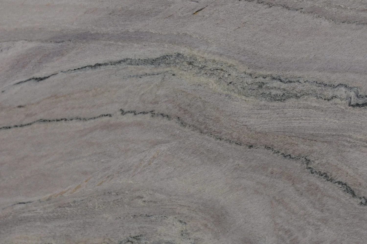 Close-up view of a light-colored stone surface with dark, wave-like veins.