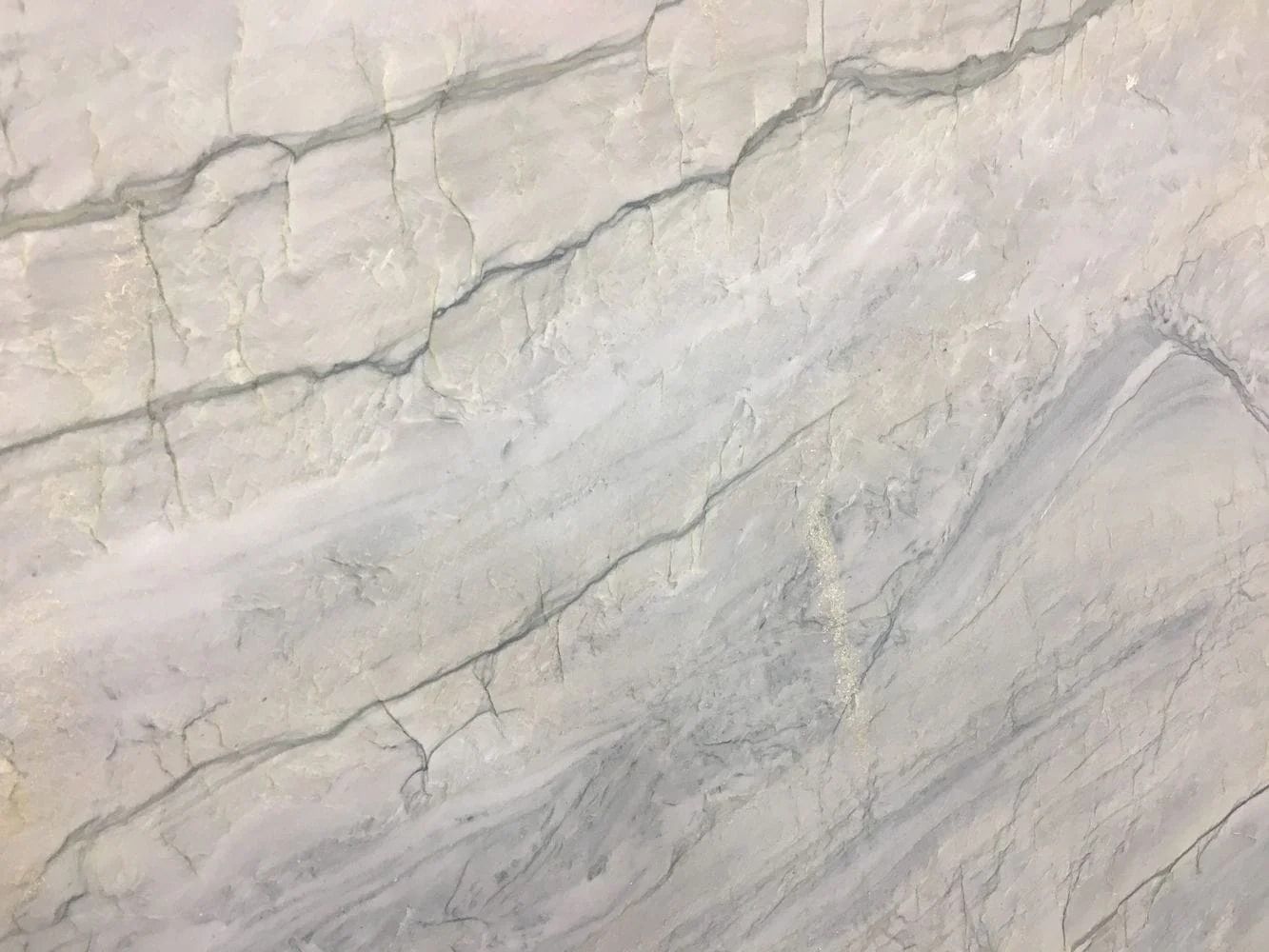 Close-up of a white marble surface with gray veins and cracks.