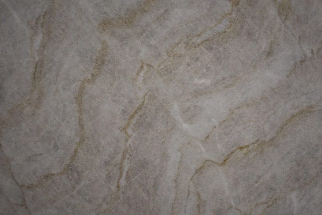Marble-like surface with swirling patterns in shades of beige and light brown.