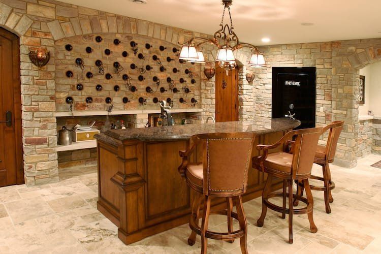 Wine bar with stone walls, wooden bar, bar stools, and a wine rack.