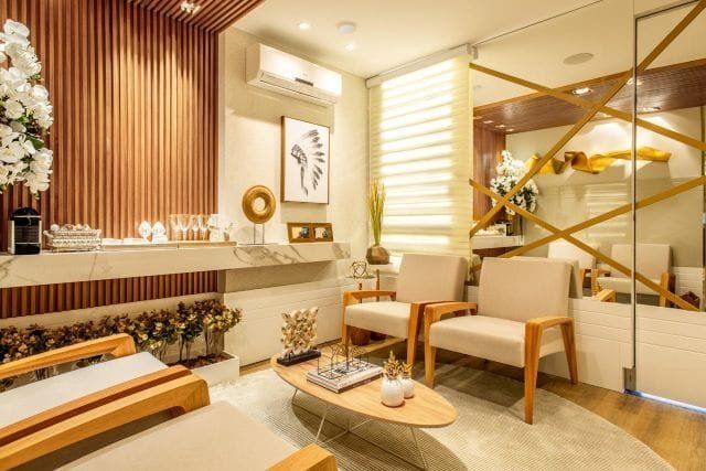 Elegant spa waiting room with wood paneling, marble counter, cream furniture, and decor.