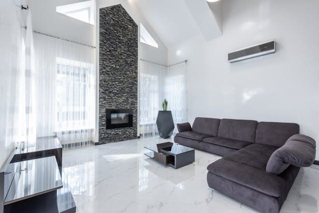 Modern living room with dark gray sectional, fireplace, and air conditioning unit.