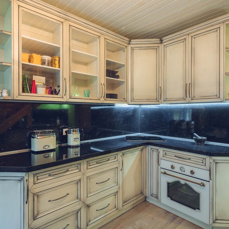 Cream-colored kitchen cabinets with a black countertop and a built-in oven.
