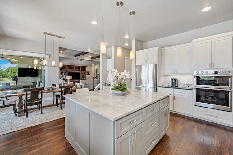 Modern kitchen with island, white cabinetry, stainless steel appliances, and wood flooring.