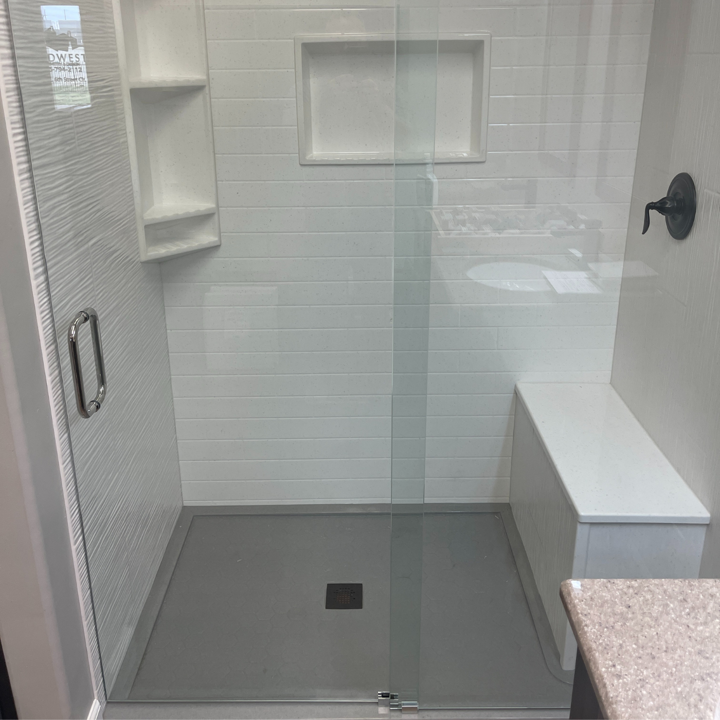 A bathroom with a walk in shower with a glass door.