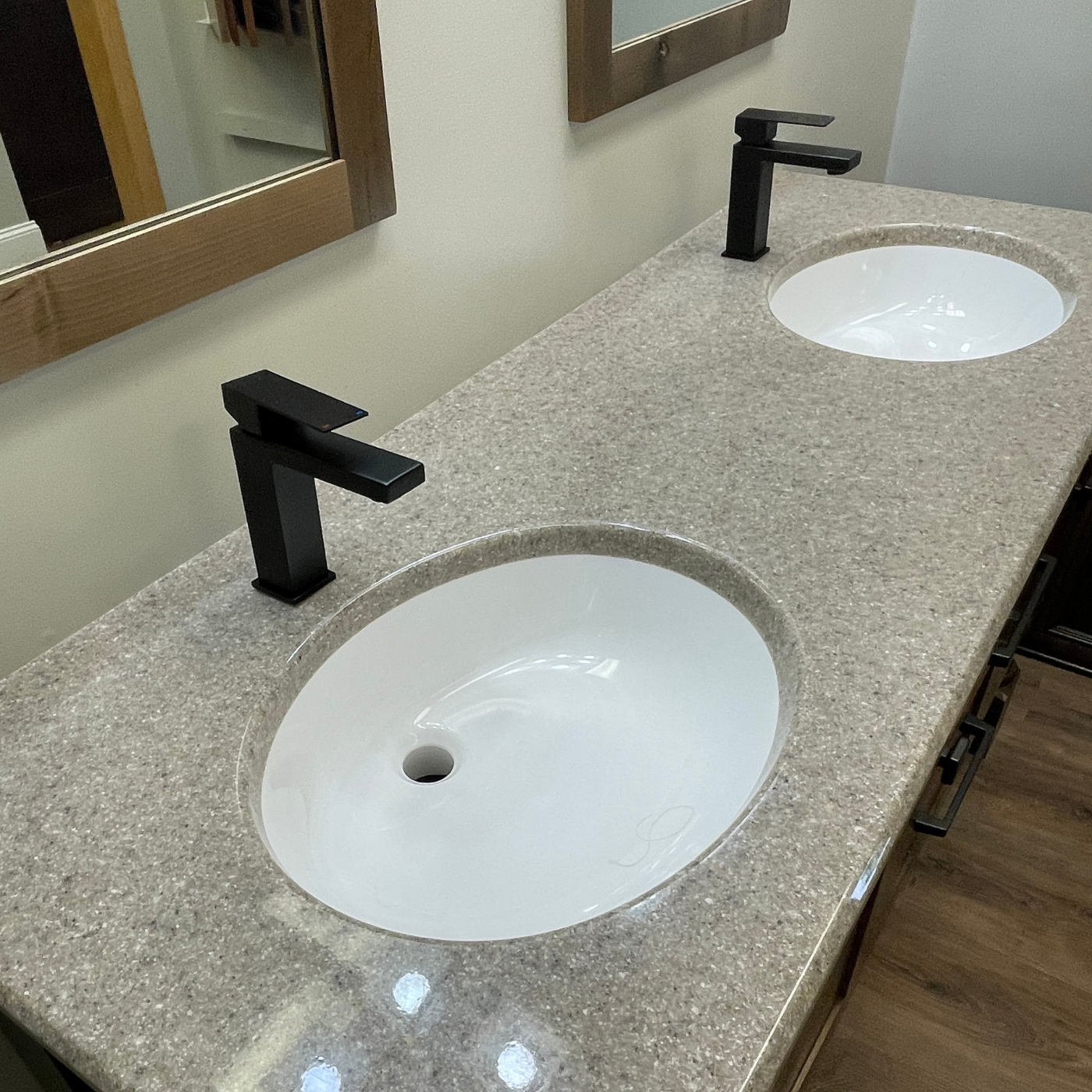 A bathroom counter with two sinks and two black faucets.