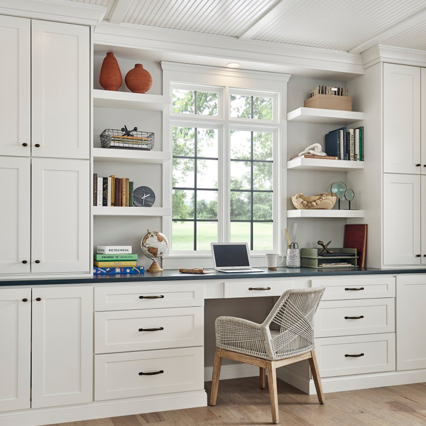 A wicker chair sits in front of a desk with a laptop on it