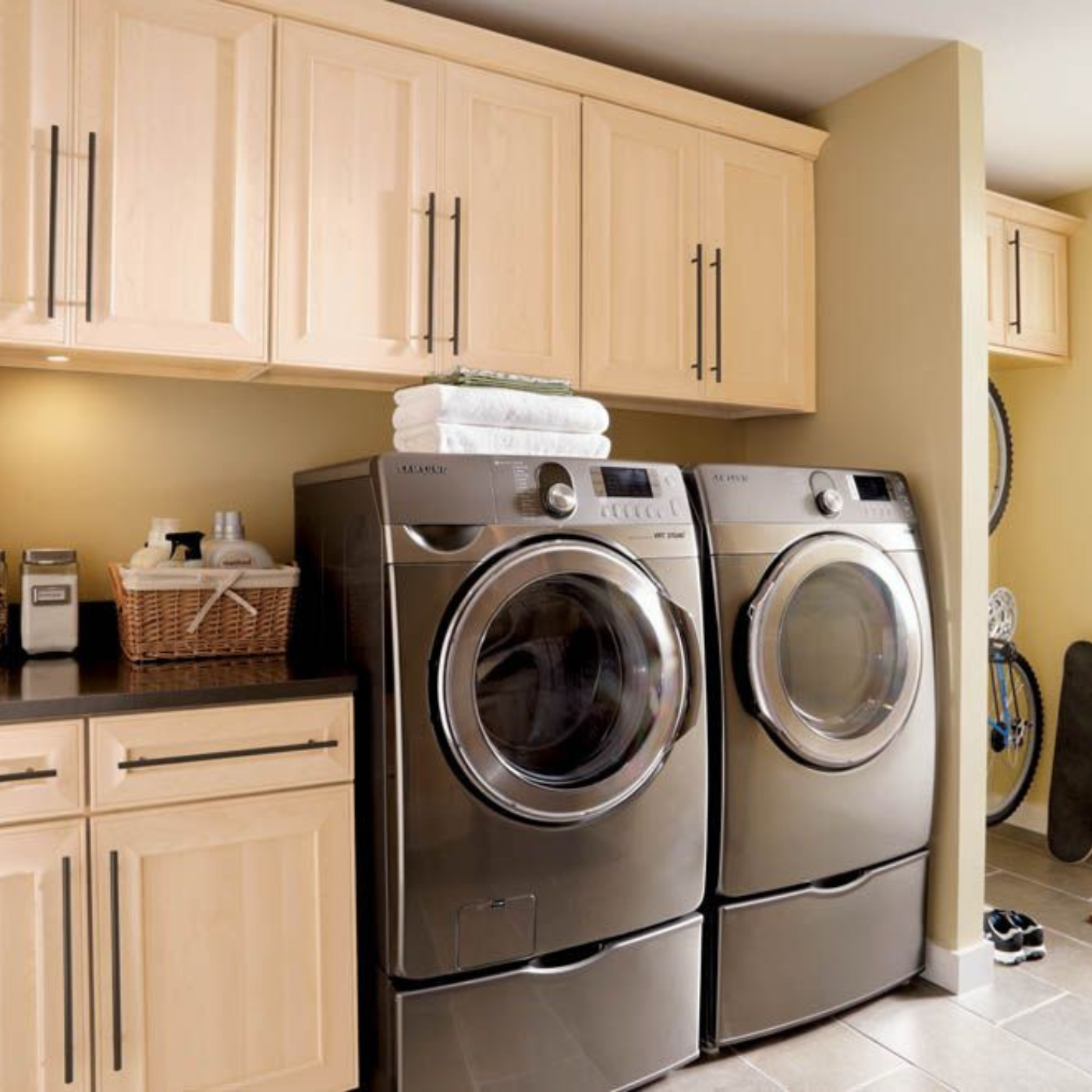 A laundry room with two stainless steel washers and dryers