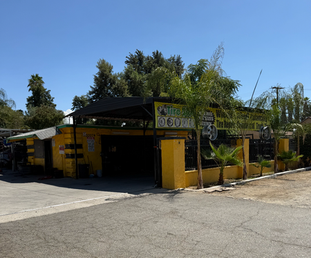 Yellow building with tiered green sculpture, decorated with flags, wind vanes in the background.