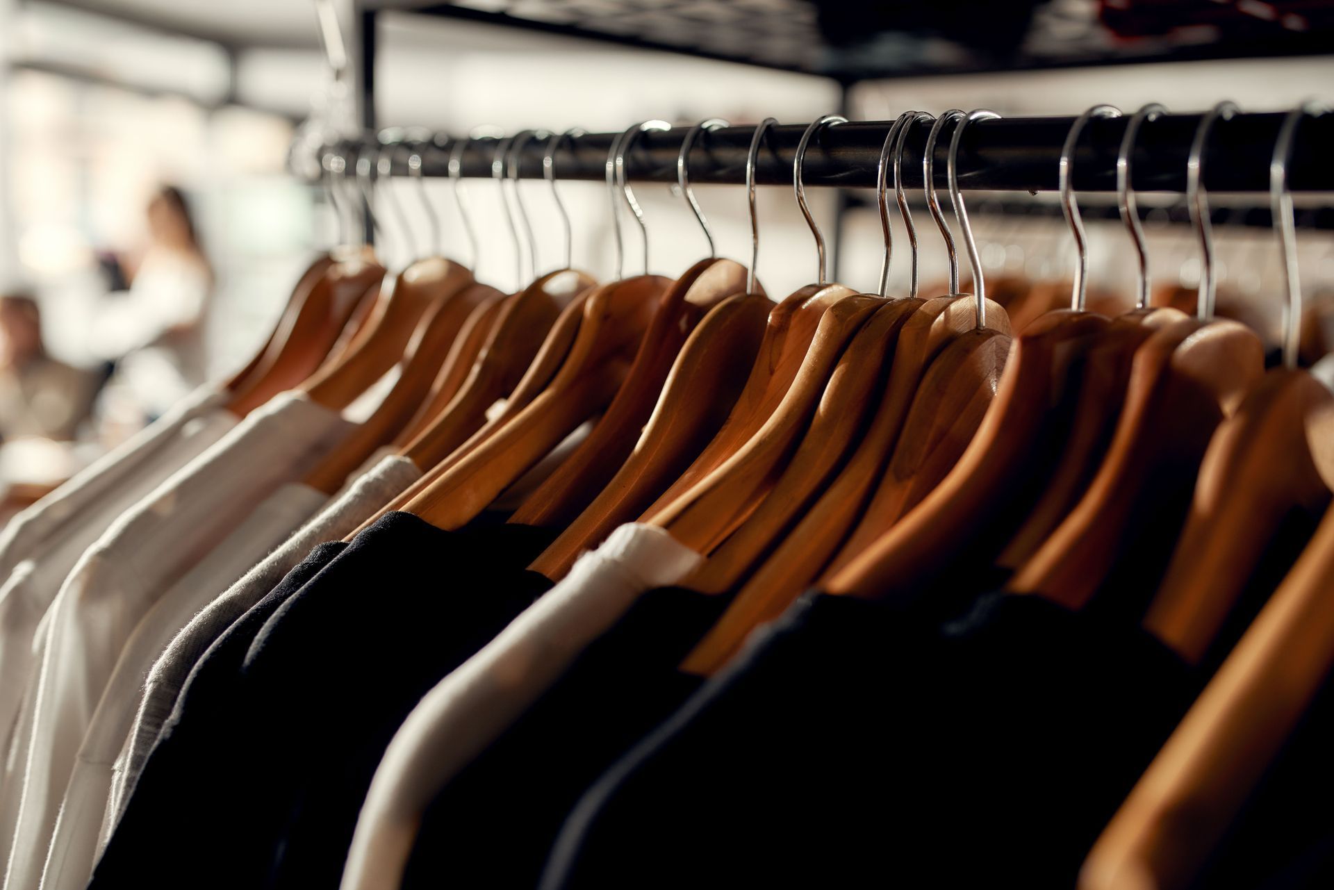 Clothes hanging on wooden hangers in a clothing store, various colors, close-up shot.