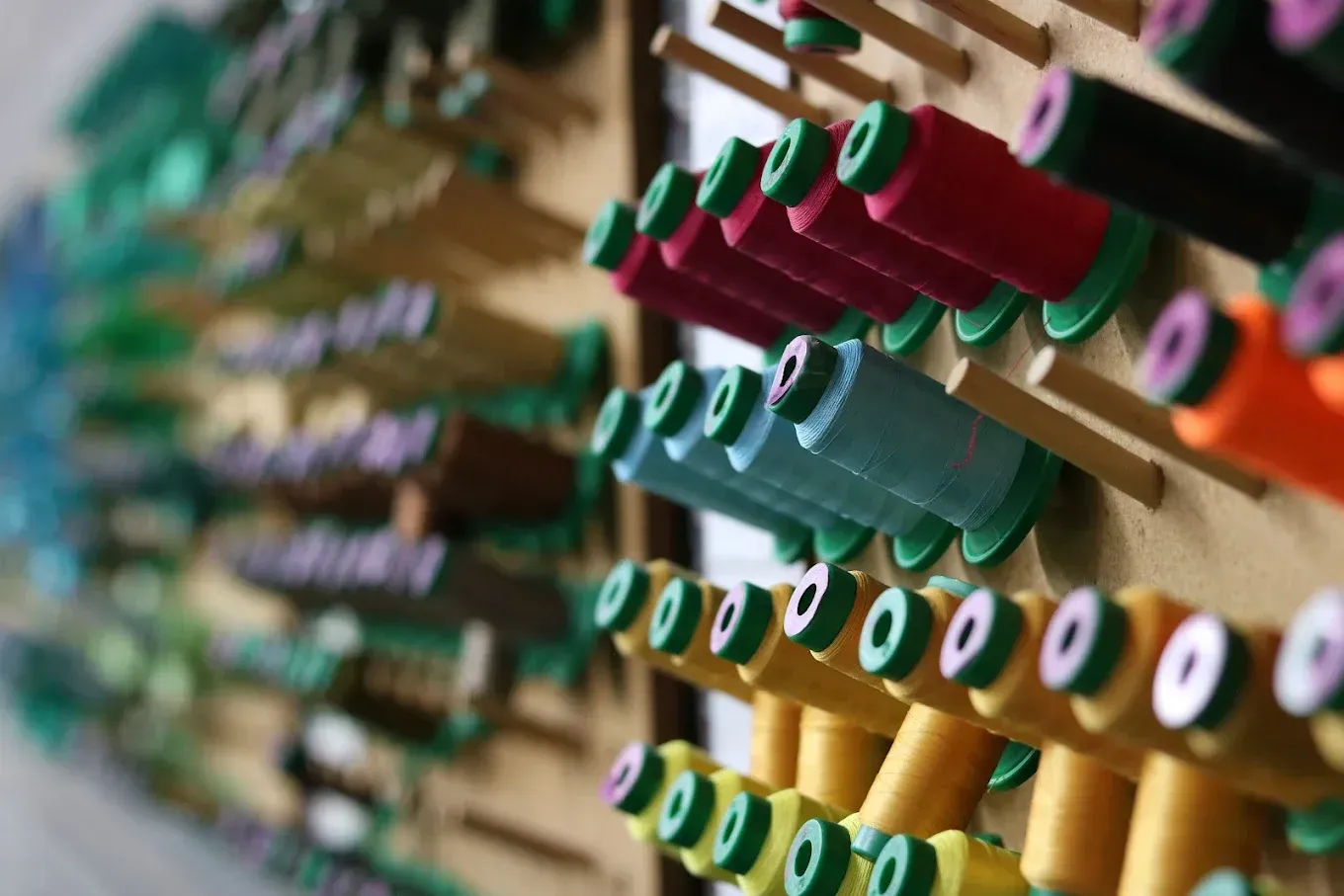 Spools of colorful thread mounted on a wooden board.
