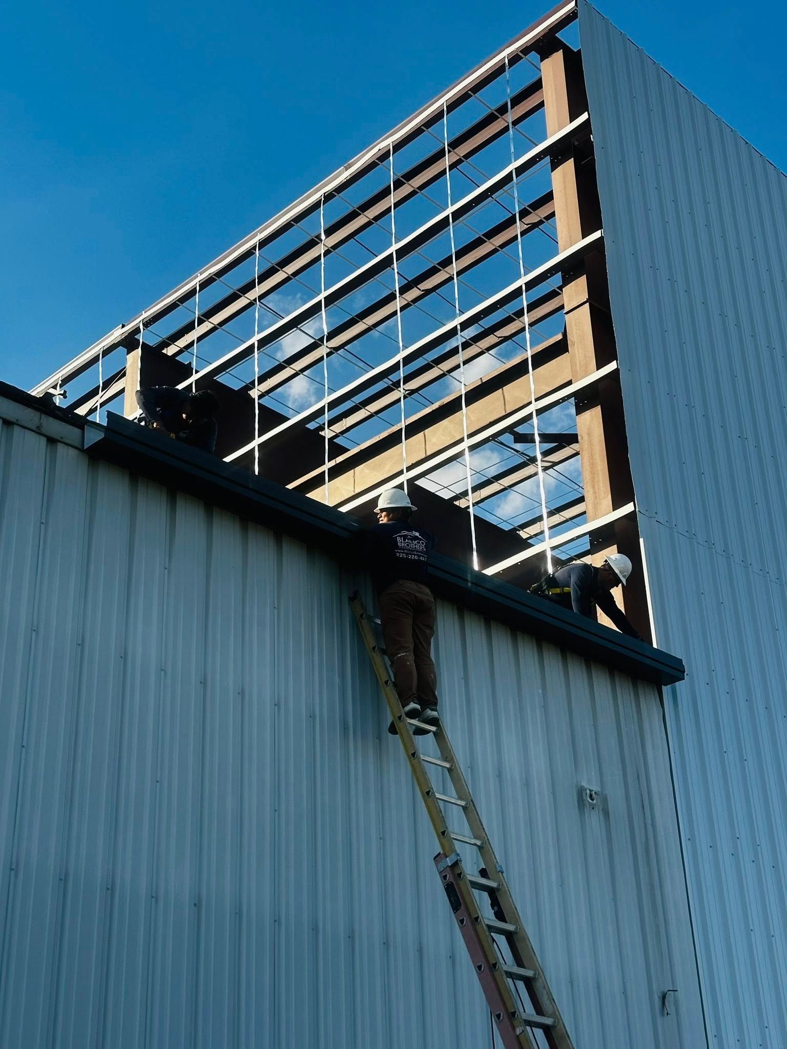 Worker on a ladder reaching a rooftop edge of a modern building