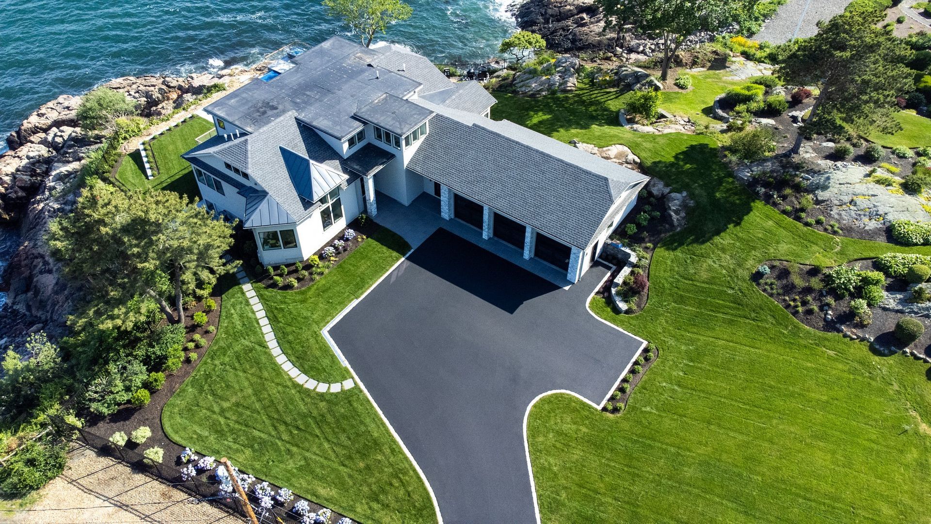 An aerial view of a large house on a cliff overlooking the ocean.
