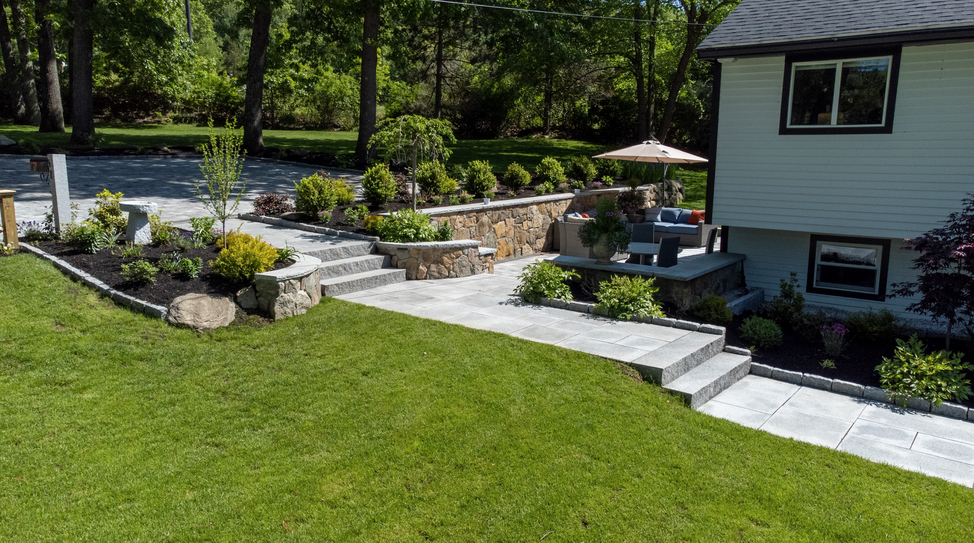 A house with a lush green lawn and a stone walkway leading to it.