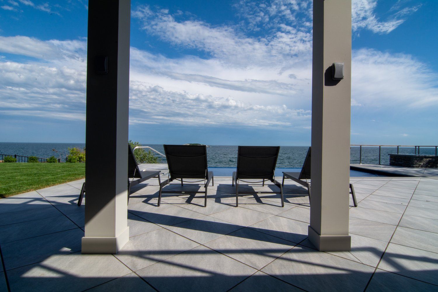 A patio with chairs and a view of the ocean.