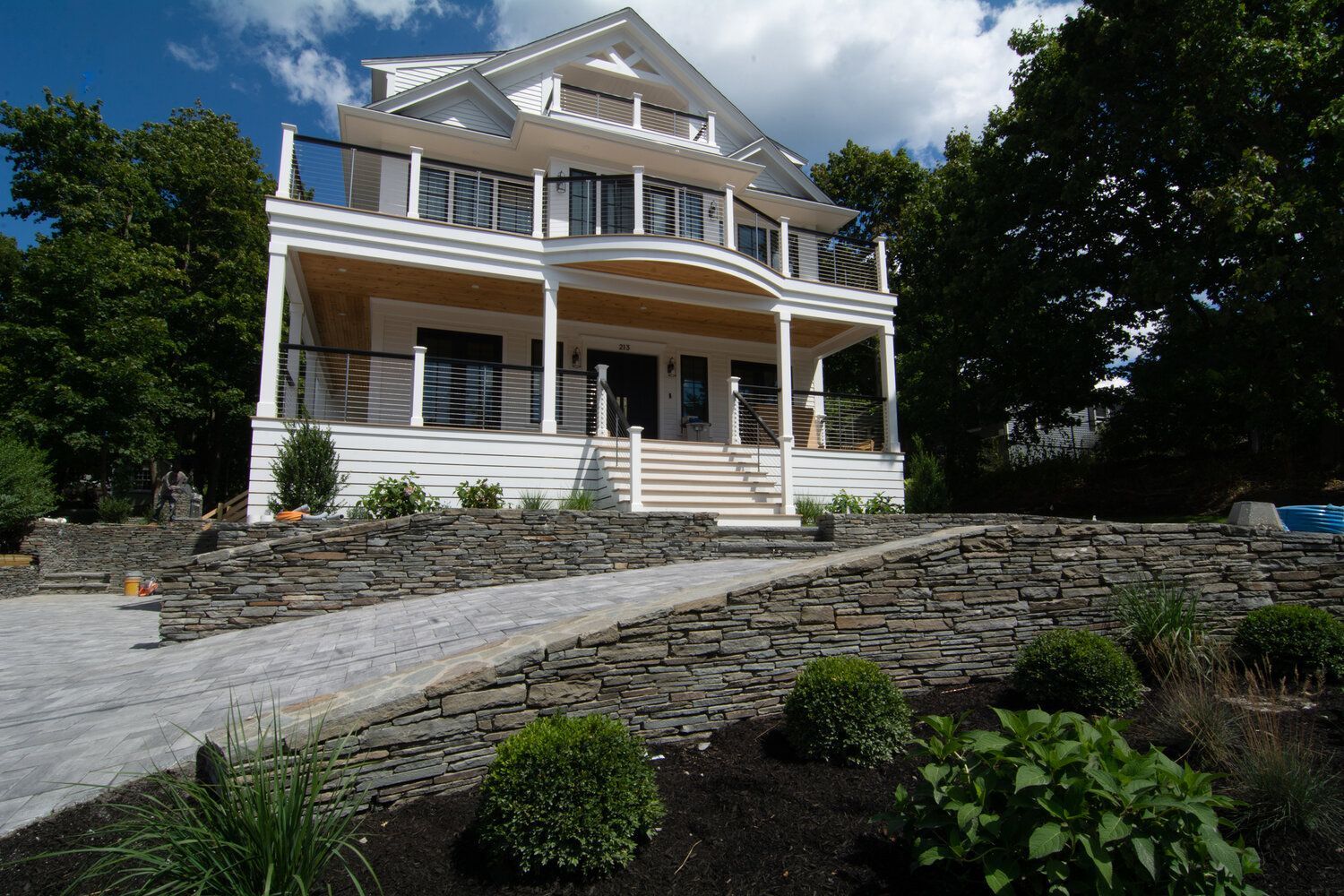 A large white house with a stone wall in front of it