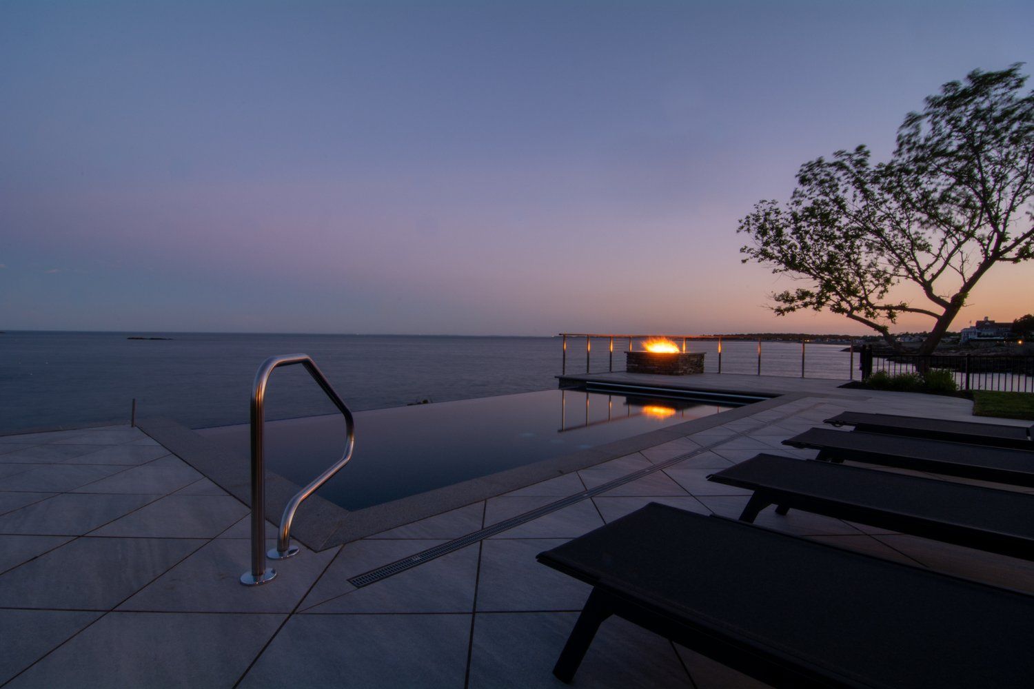 A swimming pool with a view of the ocean at sunset