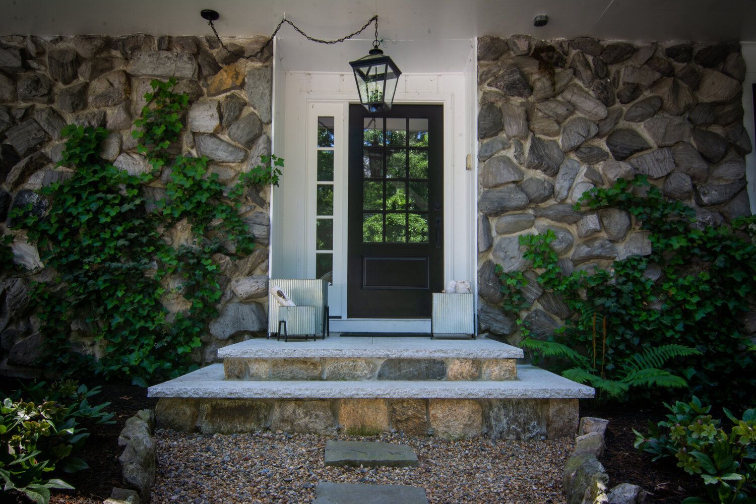 The front door of a house with a stone wall and a black door.