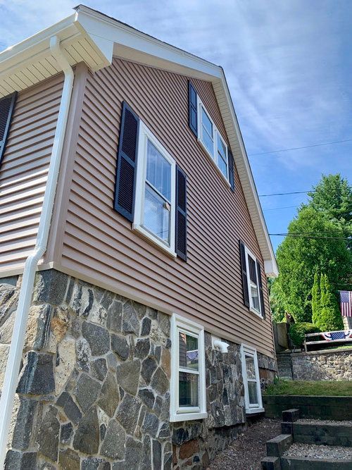 The side of a house with a stone wall and stairs leading up to it.