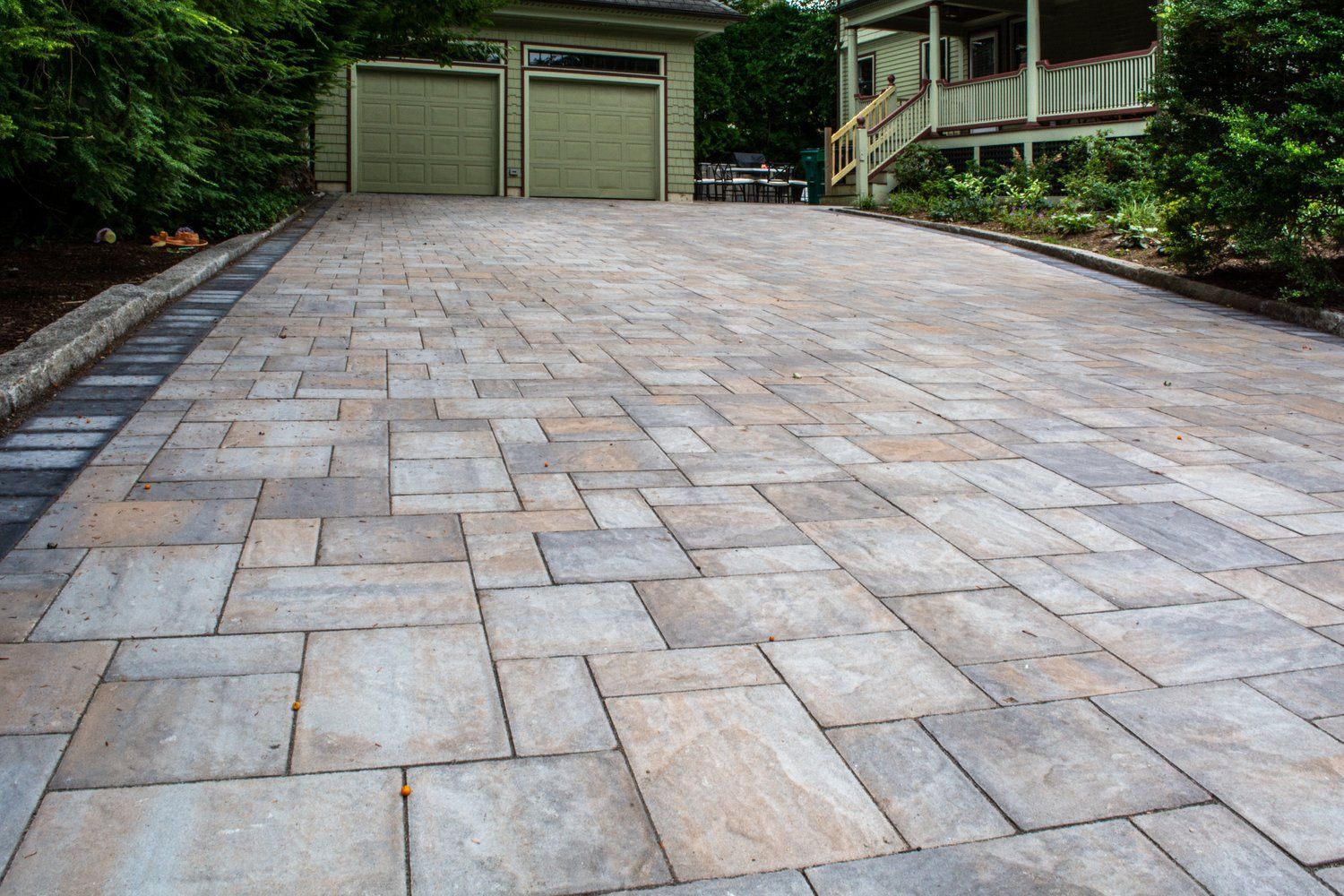 A brick driveway leading to a garage and a house.