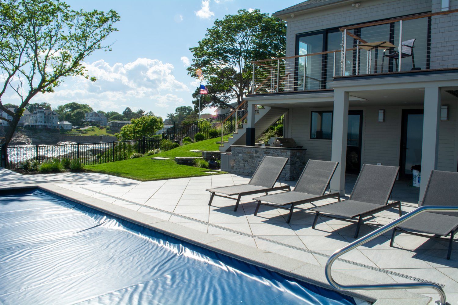 A large house with a swimming pool and lounge chairs in front of it.