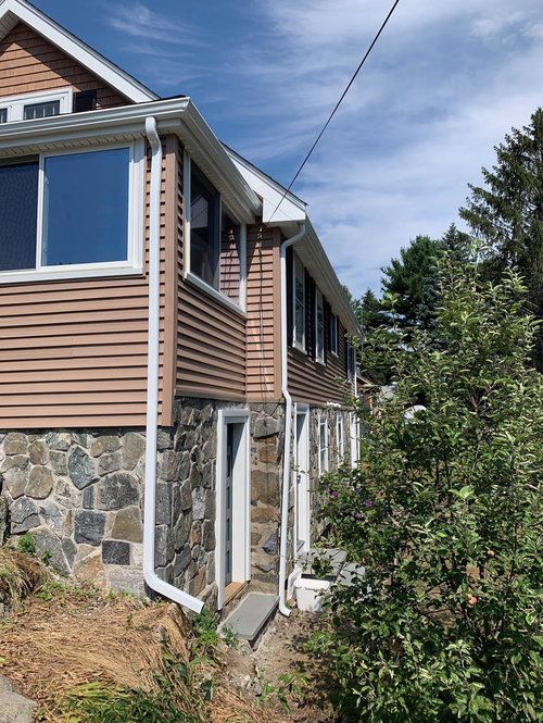 The side of a house with a lot of windows and a stone wall.