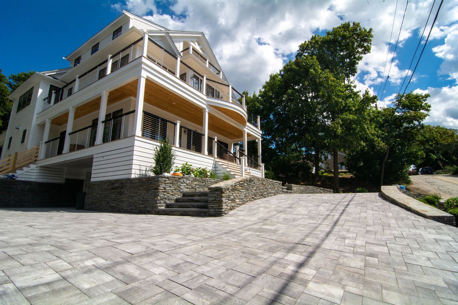 A large white house with a large porch is sitting on top of a hill.