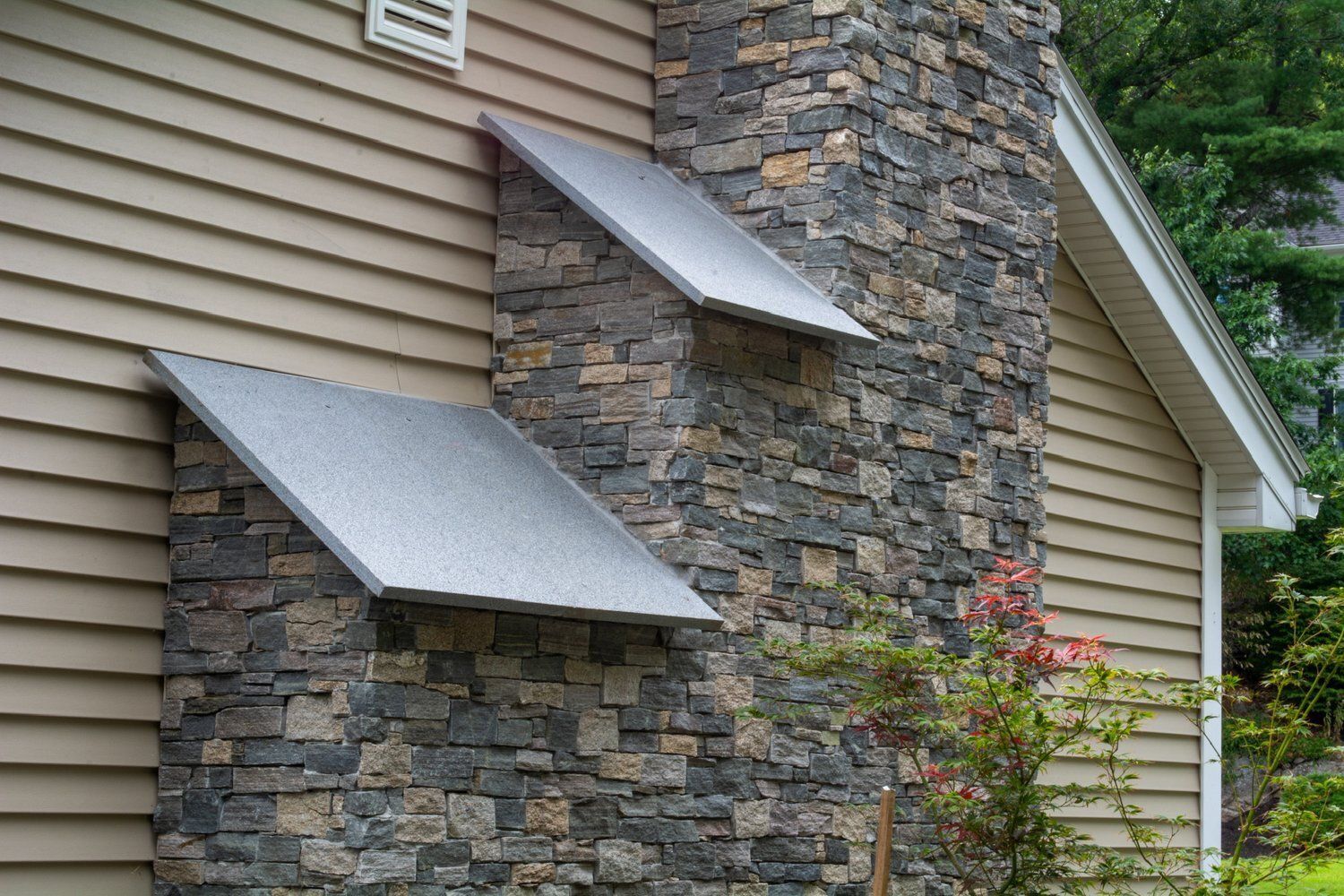 A stone chimney on the side of a house