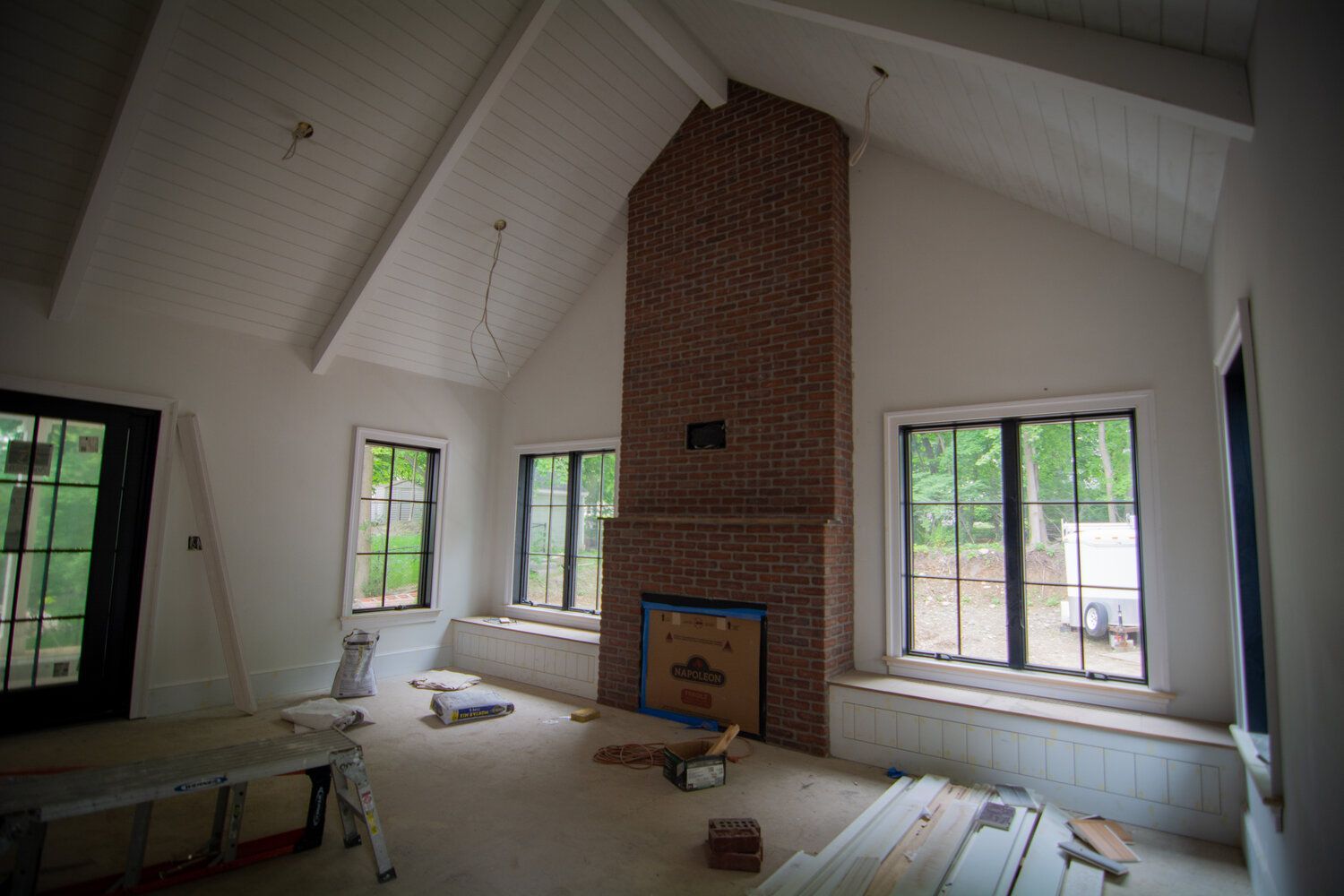 A living room with a brick fireplace and lots of windows.