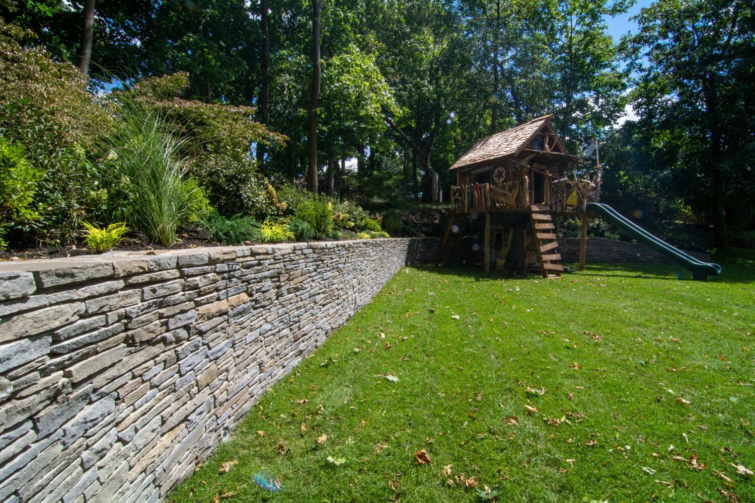 There is a tree house and a slide in the backyard.