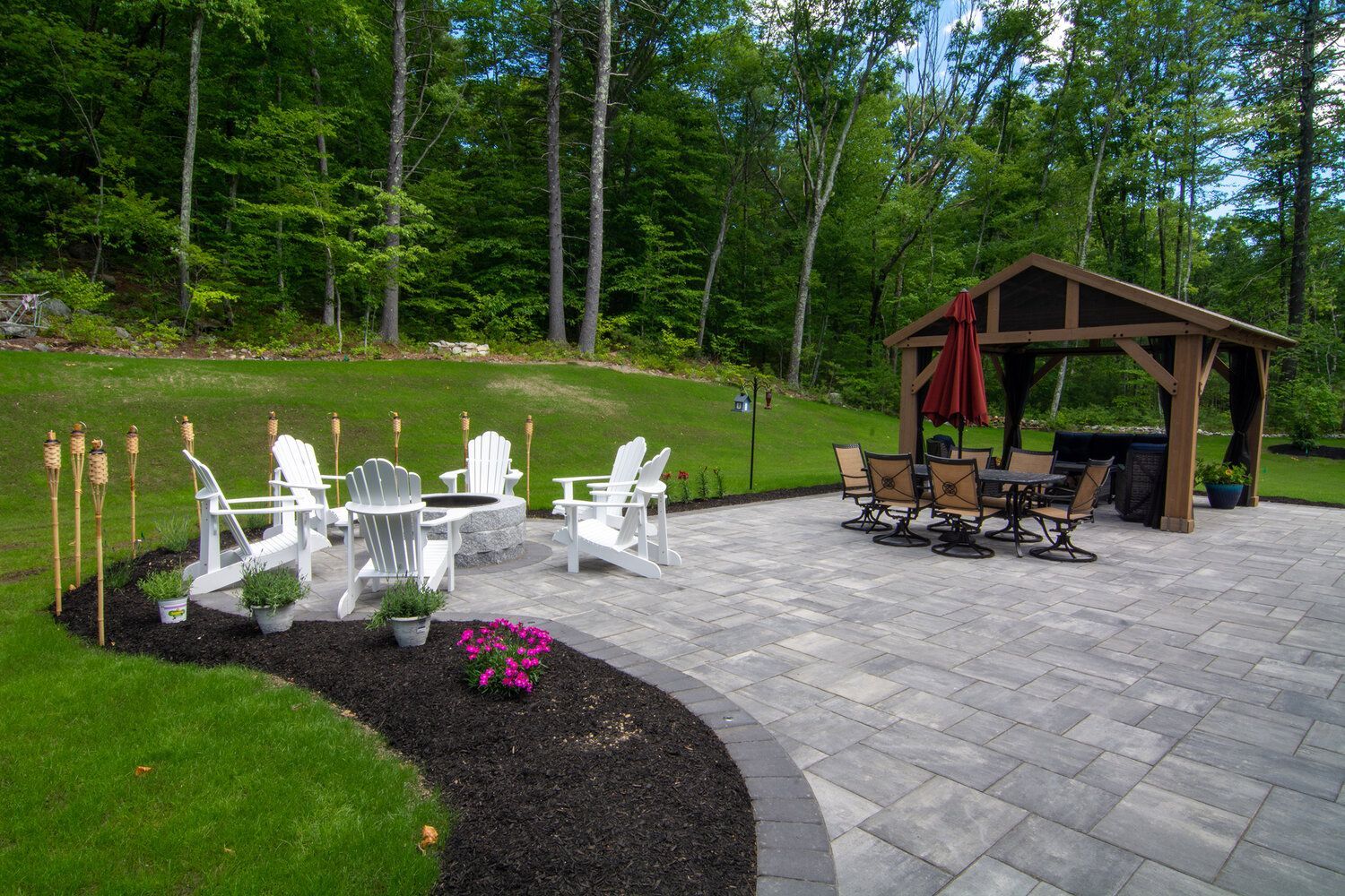 A patio with chairs , tables and a gazebo in the backyard.