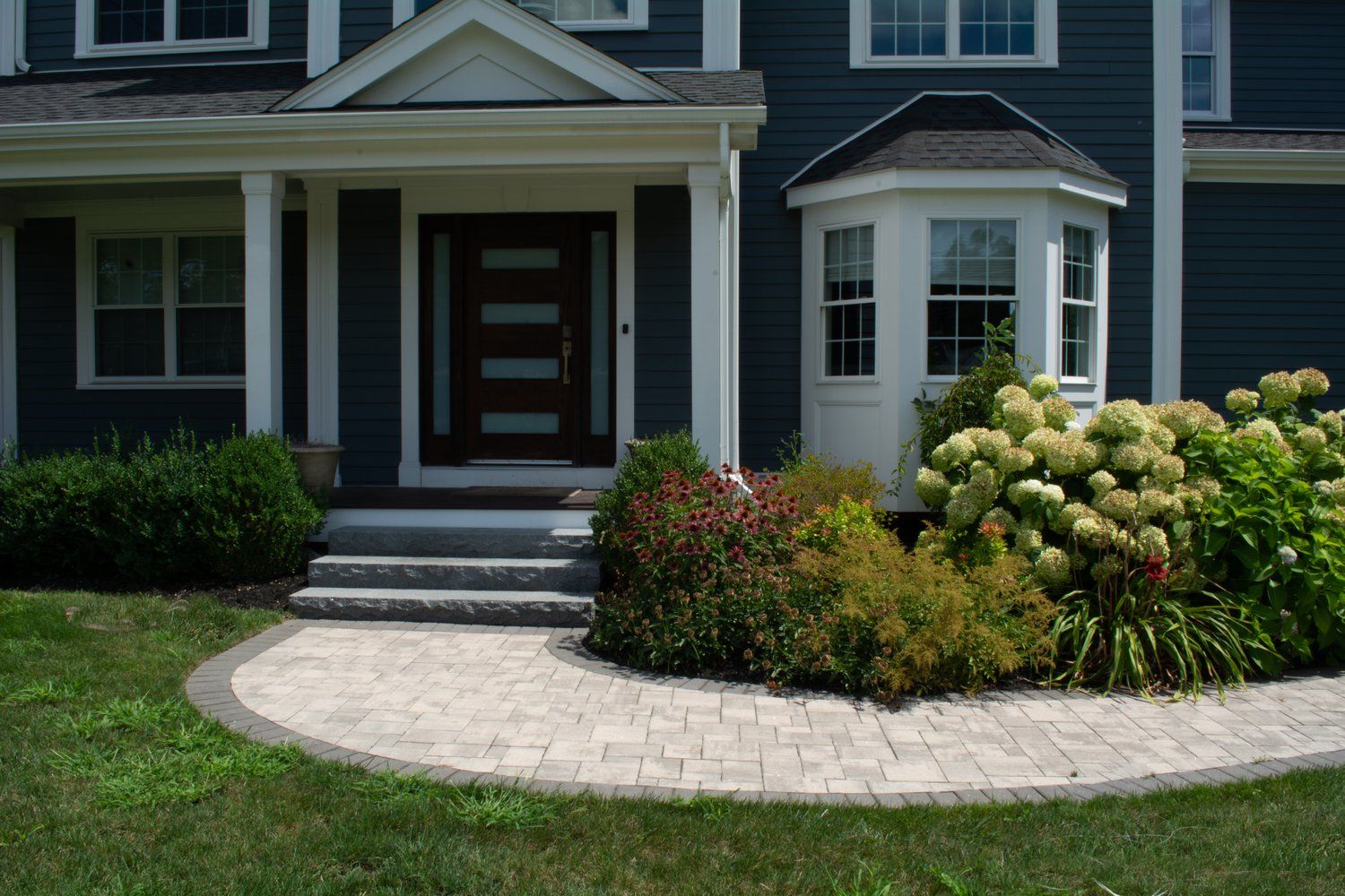 A blue house with a walkway leading to the front door