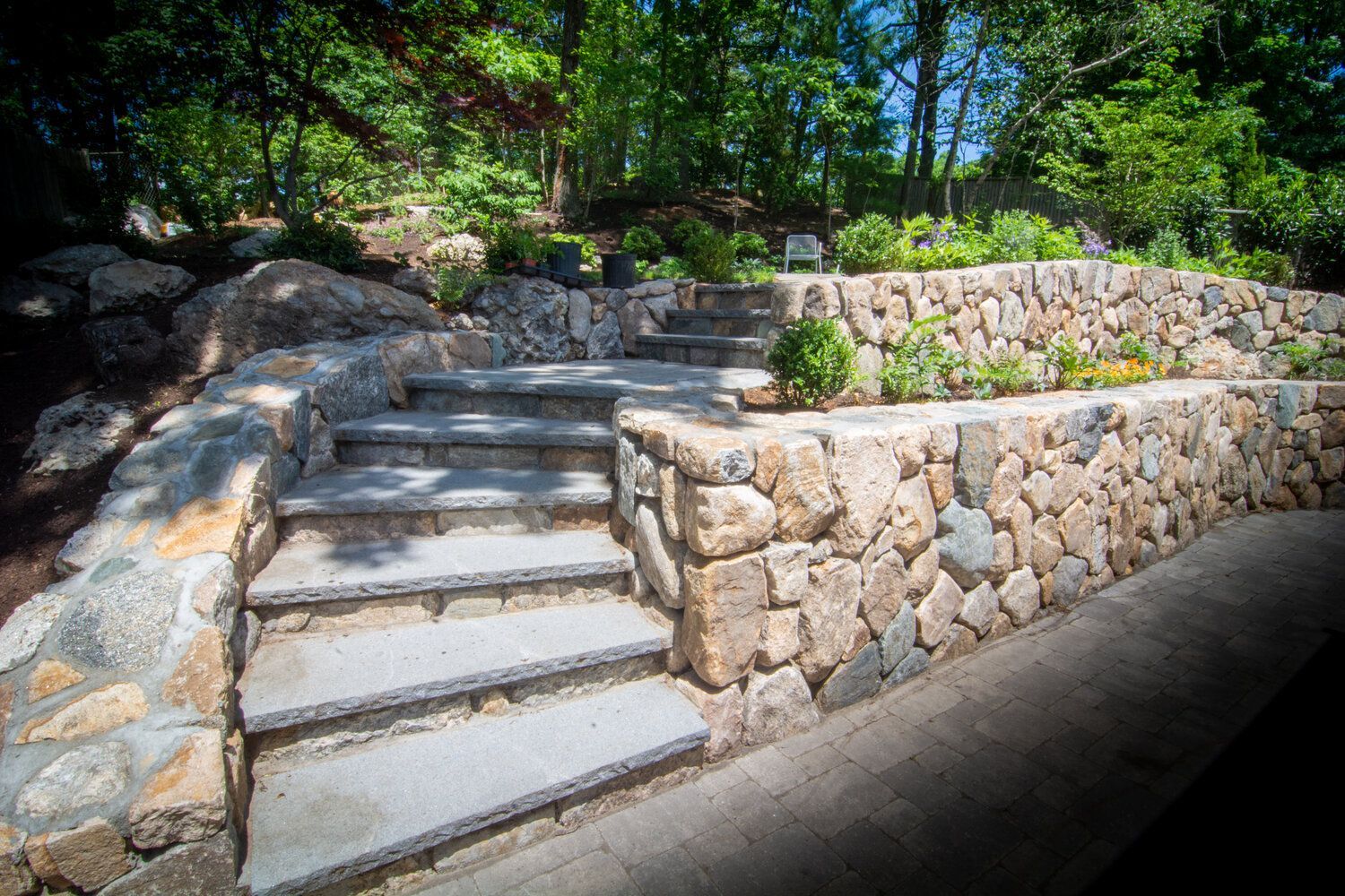A stone wall with stairs leading up to it in a garden.