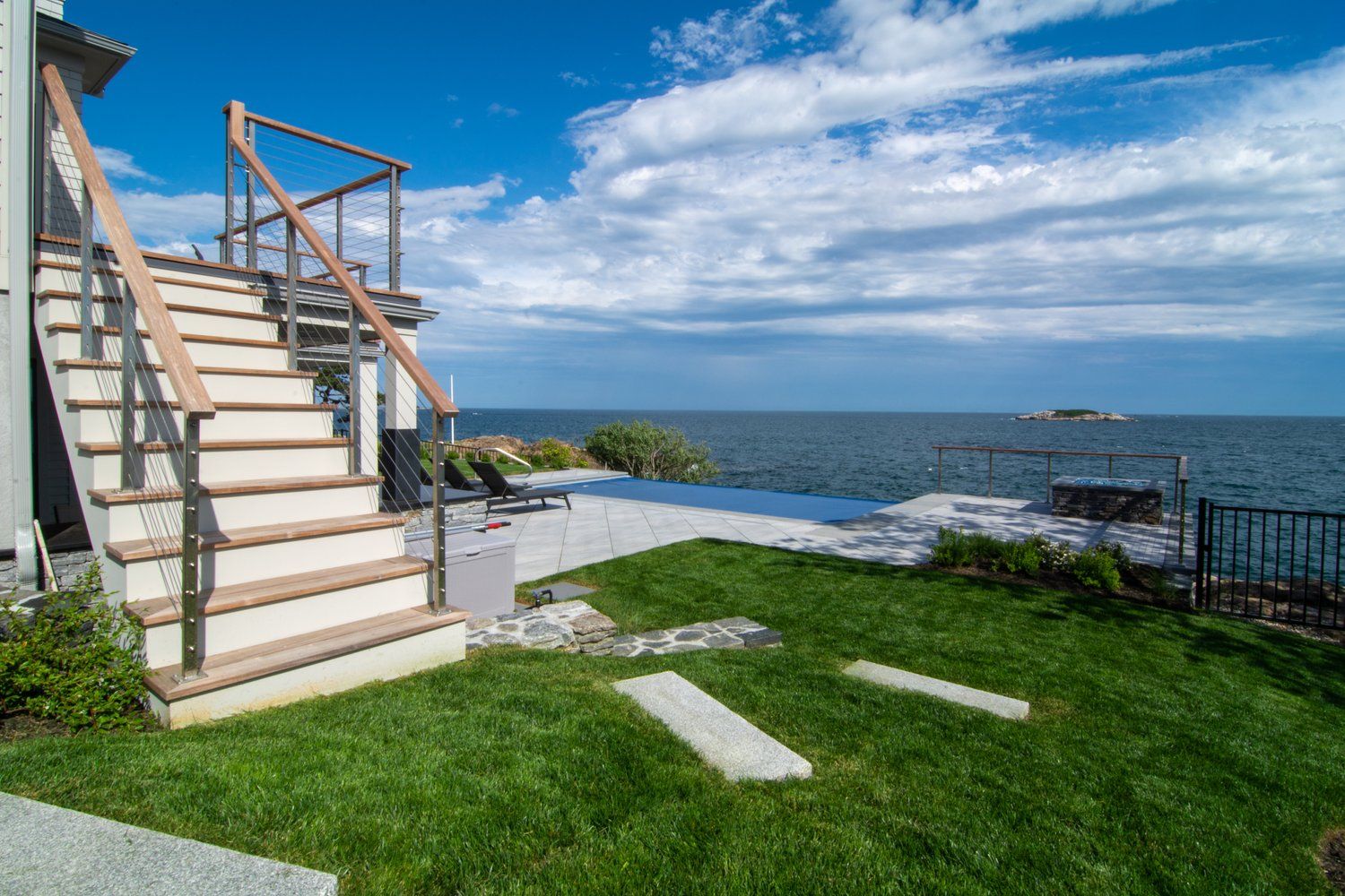 A house with stairs leading up to a deck overlooking the ocean.