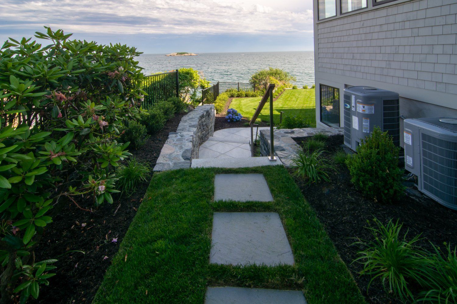 A walkway leading to a house with a view of the ocean.