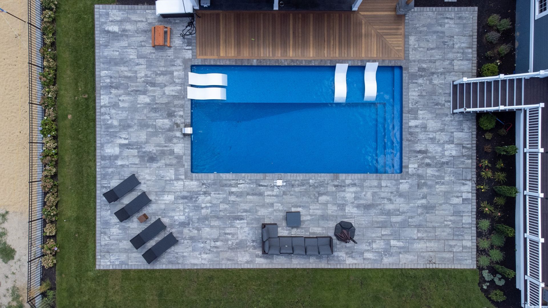 An aerial view of a large swimming pool in the backyard of a house.