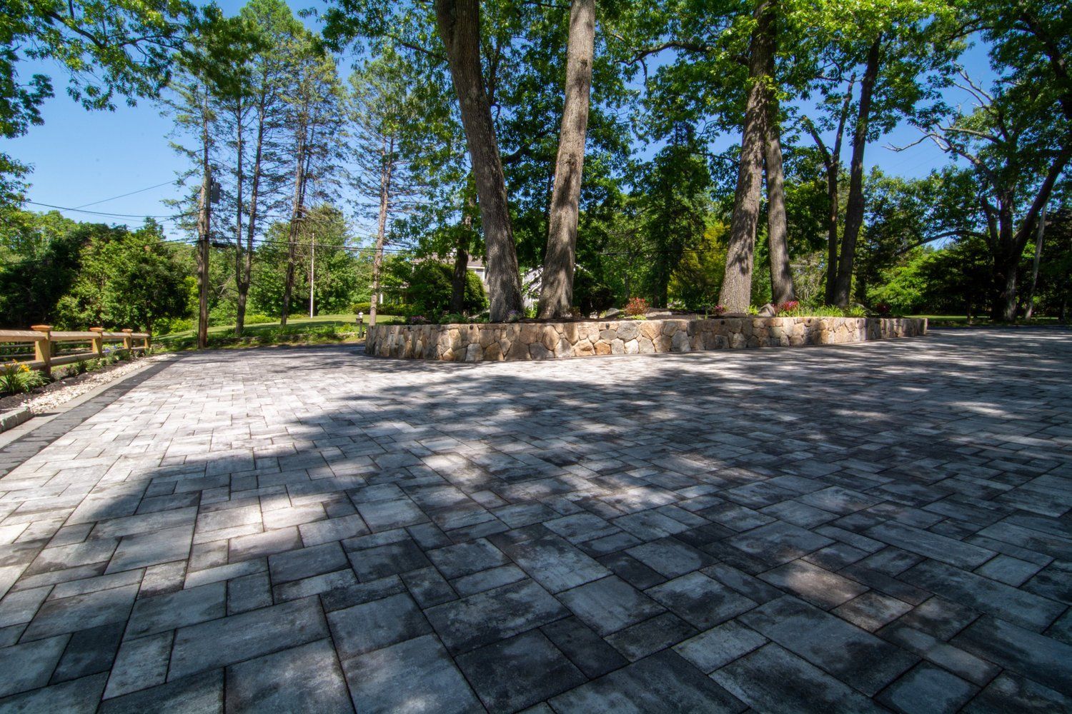 A brick driveway surrounded by trees on a sunny day.