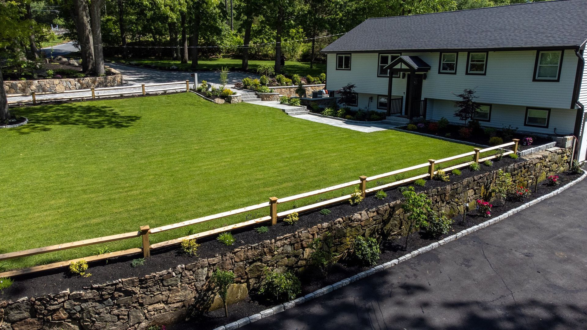 An aerial view of a house with a large lawn and a wooden fence.